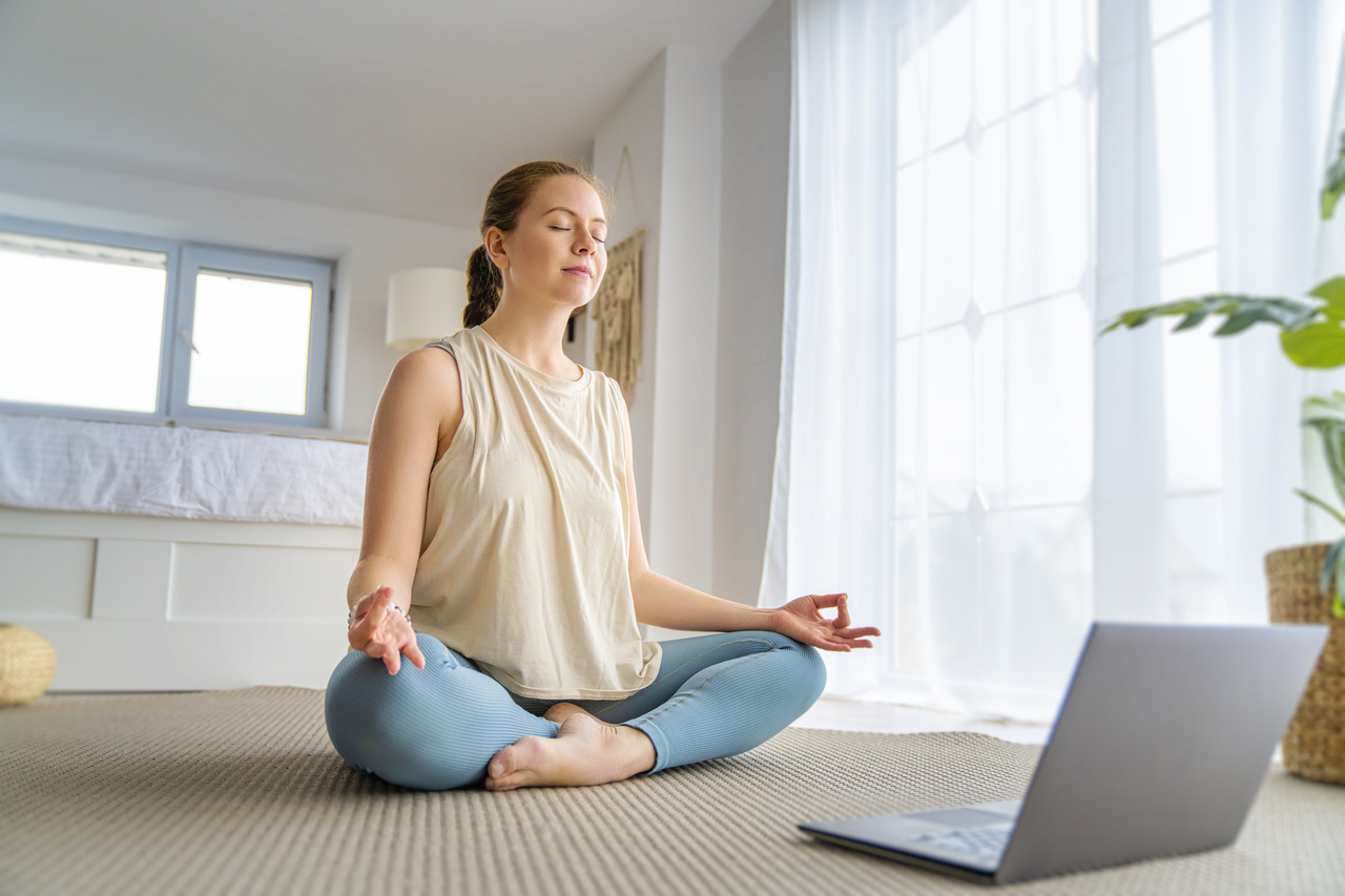 mulher meditando no chão em frente ao computador