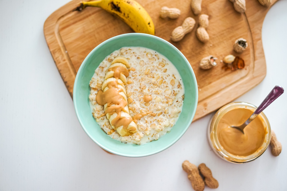 Tigela de mingau de aveia com banana e pasta de amendoim sobre uma tábua